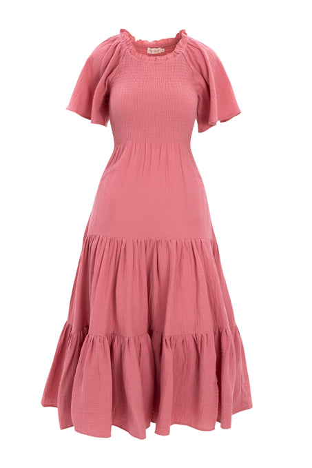 The Jovie Dress in Pink by Ivy City Co is a maternity-friendly cotton gauze dress with short sleeves, smocked bodice, ruffled neckline, and tiered skirt, crafted from lightweight textured fabric for a flowy, casual style.