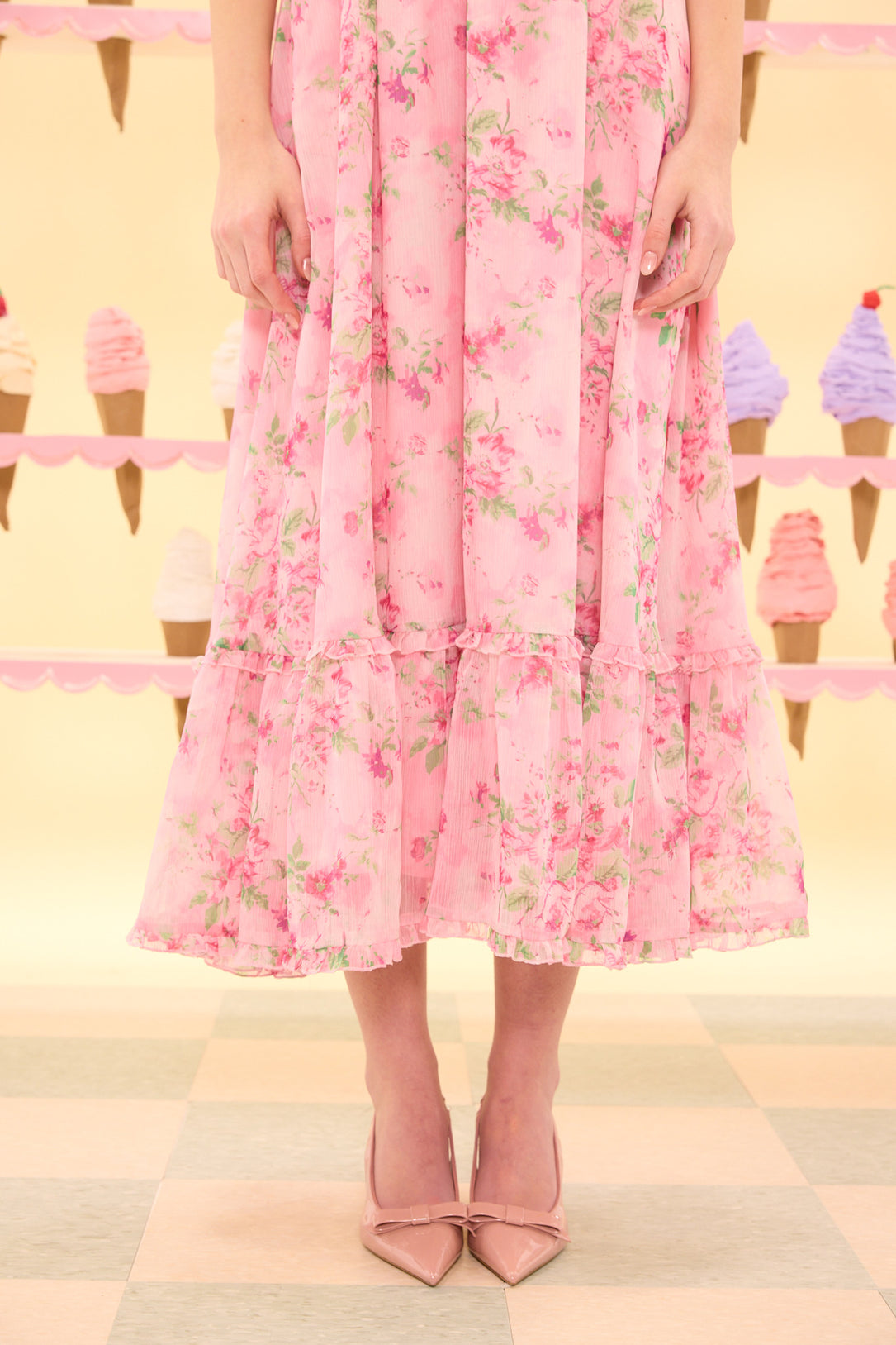 Person wearing a pink floral dress with ice cream cones in the background