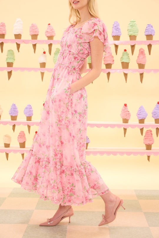 Woman in a pink floral dress standing in front of an ice cream cone display.