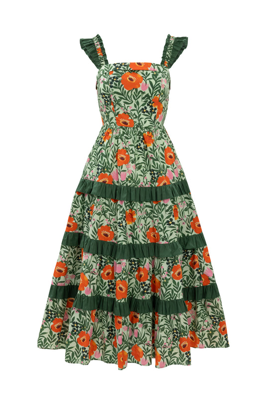 The Juno Dress in Green Floral is a sleeveless, ankle-length cotton dress with orange and pink blooms, ruffled shoulder straps, and green horizontal skirt ruffles—comfortable and chic for any occasion.