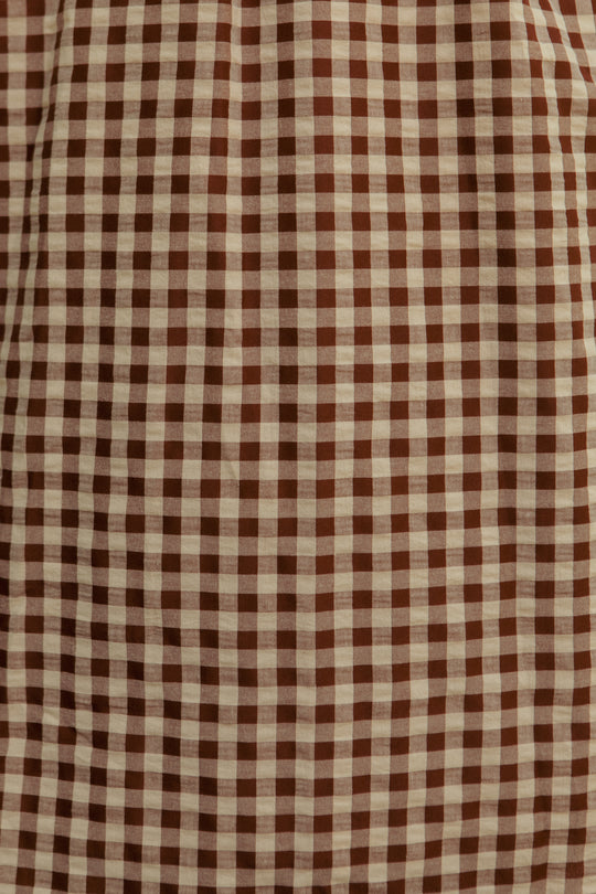 The Kaitlyn Dress in Chocolate Gingham features a brown and beige gingham fabric with a small, even checkered pattern and a textured, gently gathered top—perfect as a maternity-friendly option.