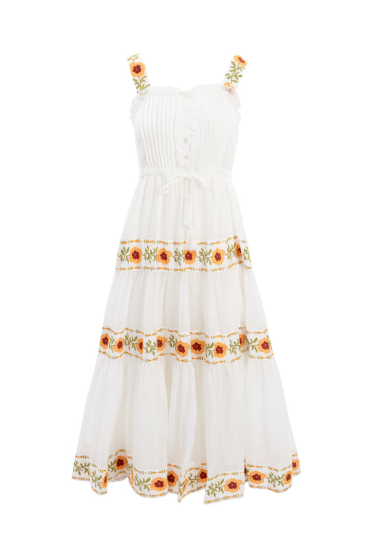 The Katerina Dress by Ivy City Co is a sleeveless white cotton midi with a smocked bodice, ruffled straps, and a tiered skirt, accented by orange, yellow, and green floral embroidery for a summery touch.