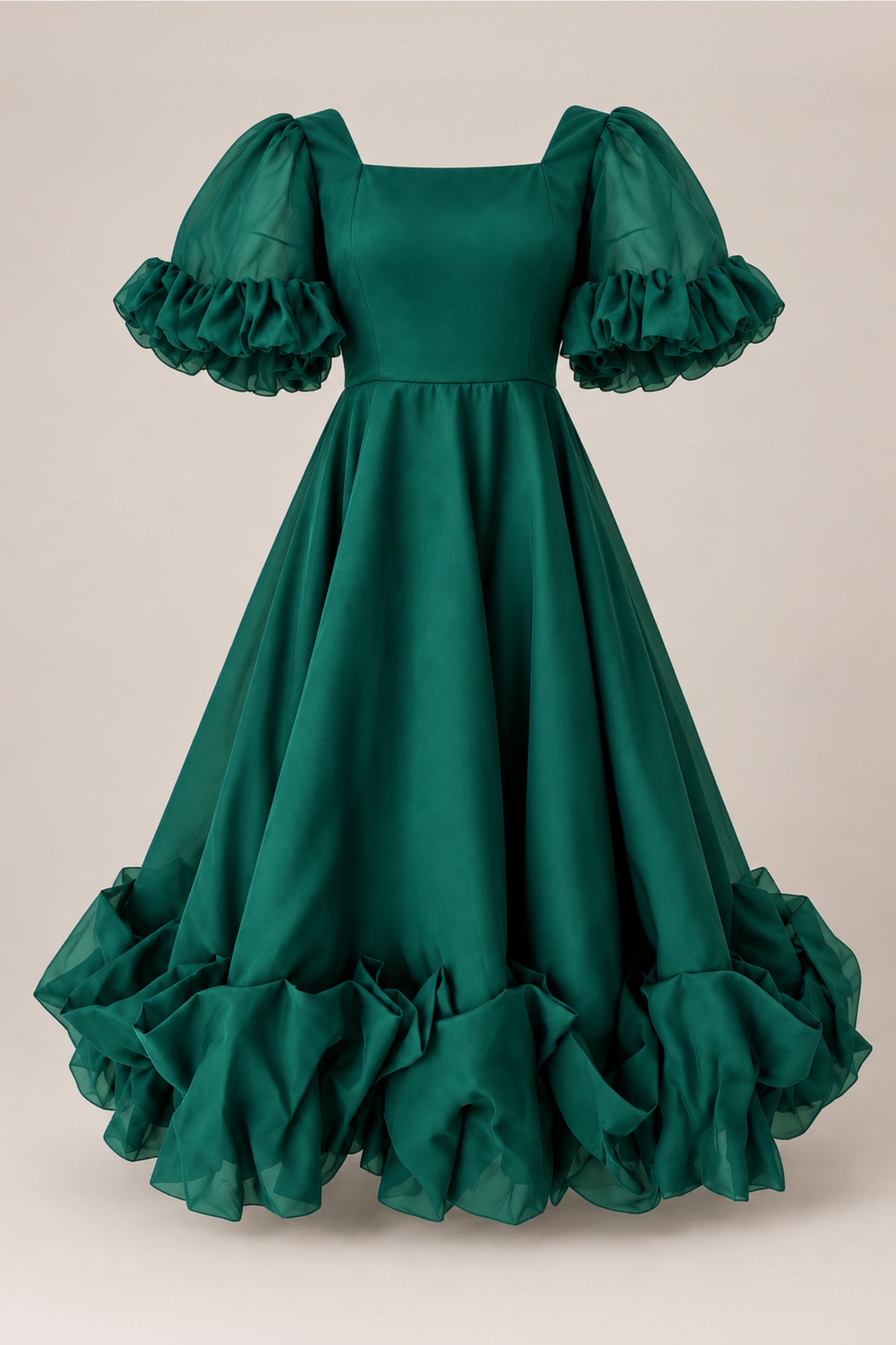 The Kendy Dress in Emerald by Ivy City Co is a floor-length gown crafted in a flowing organza A-line silhouette, showcasing puffed short sleeves with ruffled trim at the sleeves and hem. Displayed on a neutral background, this elegant dress is a perfect choice for any holiday party dress code.