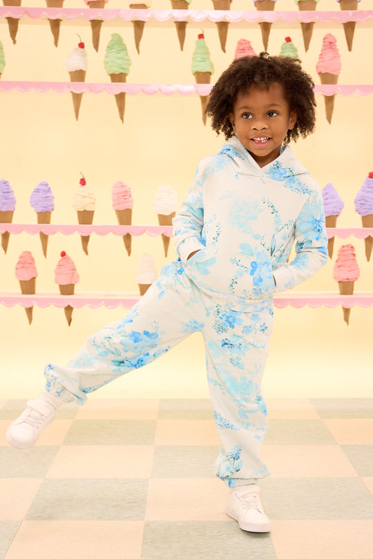 Child wearing a light blue floral outfit with ice cream cone background