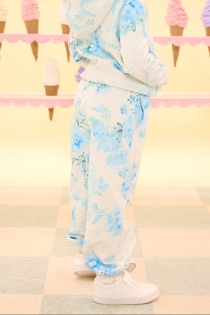 Child wearing a floral outfit standing in front of an ice cream cone patterned wall.