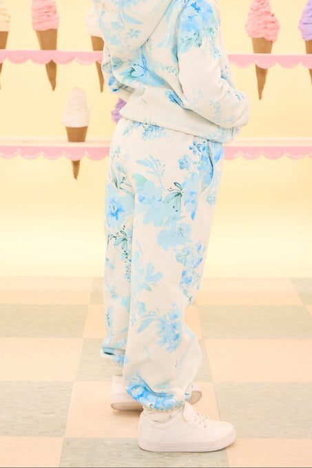 Child wearing a floral outfit standing in front of an ice cream cone patterned wall.