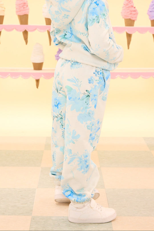 Child wearing a floral outfit standing in front of an ice cream cone patterned wall.
