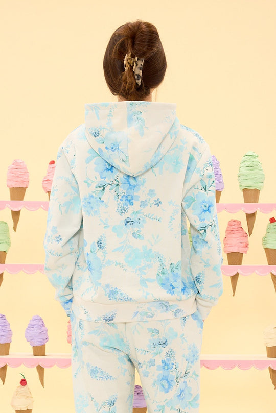 Person wearing a blue and white cloud-patterned onesie in front of ice cream cone display.