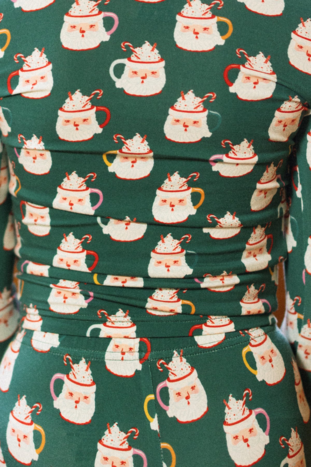 A child wears the Ivy City Co Kids So Soft Pajama Set in Very Merry Santa, featuring festive mugs, candy canes, and smiling faces—perfect for cheerful holiday family matching pajamas.