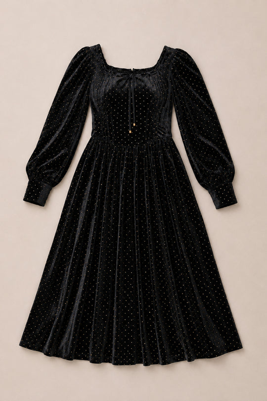 The Kingston Dress in Black by Ivy City Co is a stunning black velvet midi dress featuring long puffed sleeves, a square neckline, and shimmering gold polka dot embellishments. This elegant dress offers a fitted bodice and a flared skirt, beautifully displayed on a neutral background.