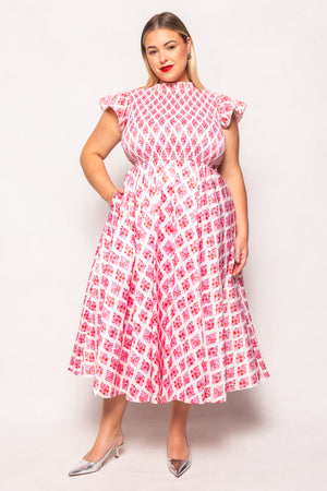 Woman wearing a pink and white patterned dress on a plain background