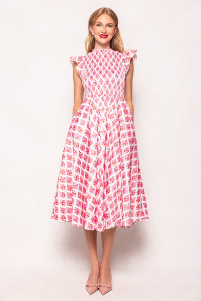 Woman wearing a pink and white patterned dress against a light background