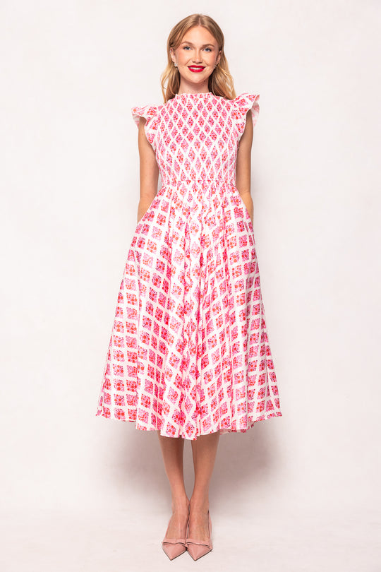Woman wearing a pink and white patterned dress against a light background