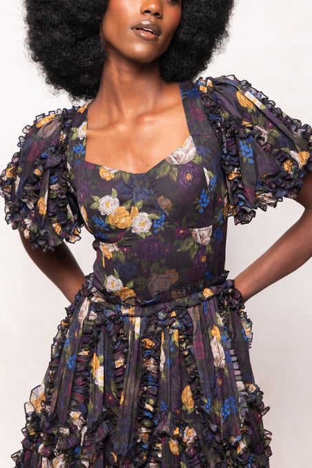 Woman wearing a floral dress with ruffled sleeves against a white background
