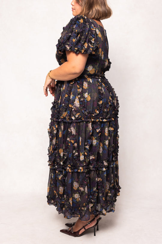 Woman wearing a floral tiered dress on a white background