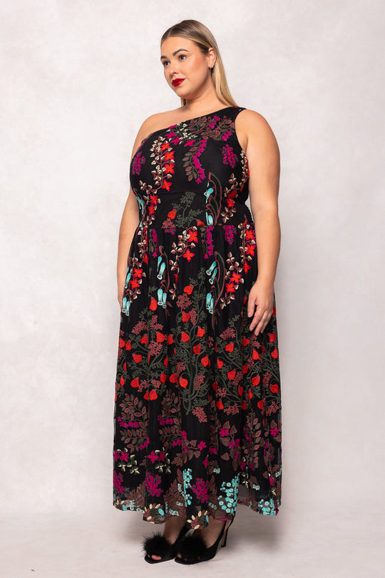 Woman wearing a floral one-shoulder dress against a white background