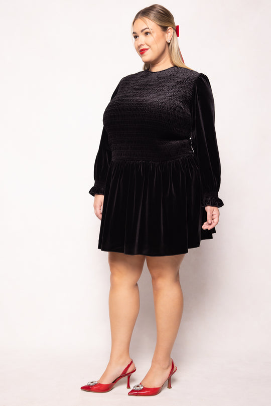 Woman wearing a black dress with red shoes on a white background