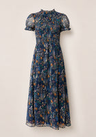 Discover the Leonora Dress in Midnight Autumn Bouquet by Ivy City Co—a navy blue, midi-length dress with short, sheer puff sleeves and a high ruffled collar. Featuring a beautifully smocked bodice, this elegant piece is decorated with an autumn-inspired floral print in orange, white, and green, and finished with a flowy skirt for effortless charm.