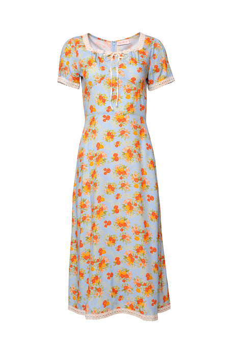 The Libby Dress in Orange Floral by Ivy City Co is a light blue, short-sleeved midi with a fitted waist, orange floral print, round neckline with tie, and white crochet lace trim on the sleeves and hem.