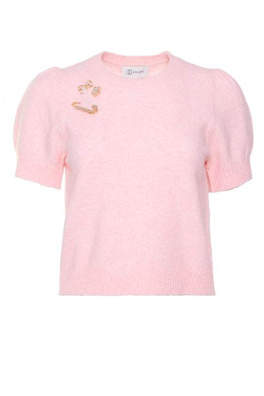 Pink sweater with gold pin accents against a white background
