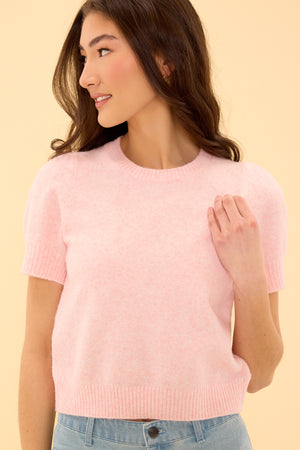 Woman wearing a pink sweater against a beige background