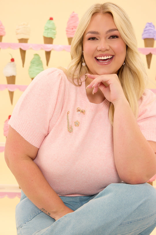 Woman in a pink shirt with a gold bow pin sitting in front of ice cream cones on a yellow background