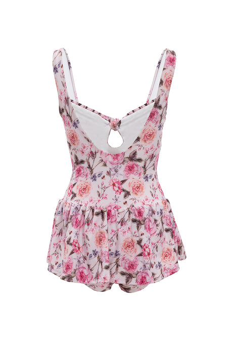 The Lola Swim Dress in Ballerina Pink Floral by Ivy City Co is a one-piece swim dress with a skirted bottom, wide straps, full coverage, a keyhole back cutout, and pink and purple roses on a white background.