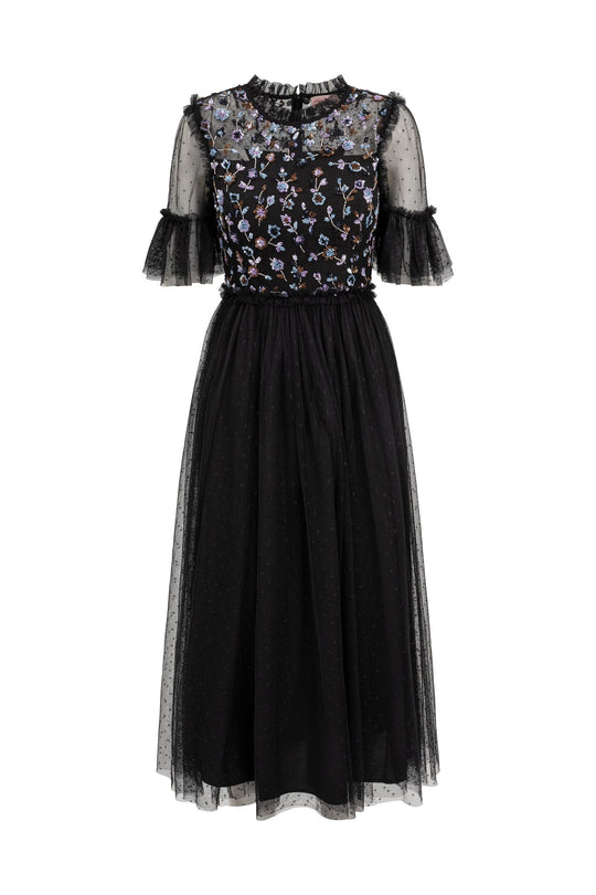 The Louisa Dress in Black by Ivy City Co is a stunning midi dress featuring sheer short sleeves, ruffle details, and a graceful tulle overlay. This elegant black tulle dress showcases delicate pastel floral embroidery on the bodice and a subtly dotted skirt for added charm.