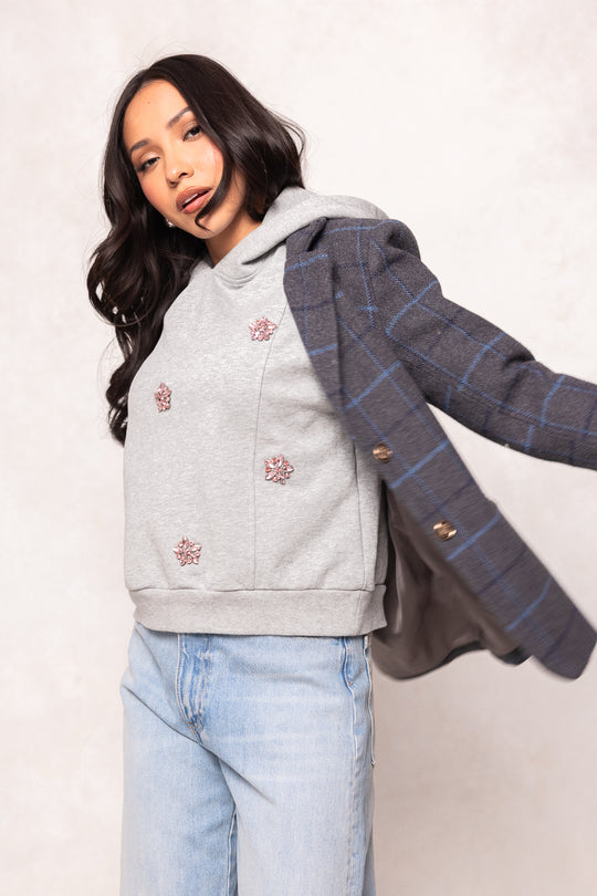 Girl in a grey hoodie and jeans and a blazer against a white background