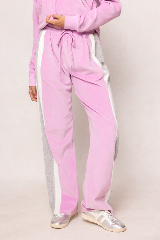 Person wearing a pink tracksuit with white stripes on a plain background