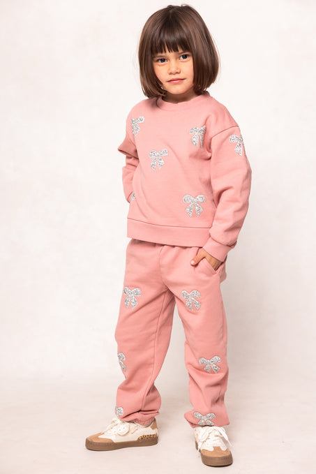 girl in a pink sweatsuit against a white background