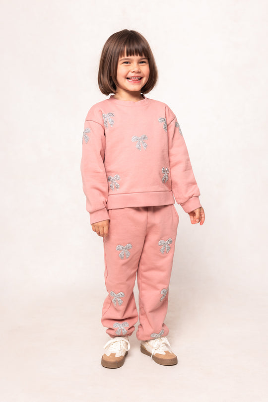 child in a pink sweatsuit against a white background