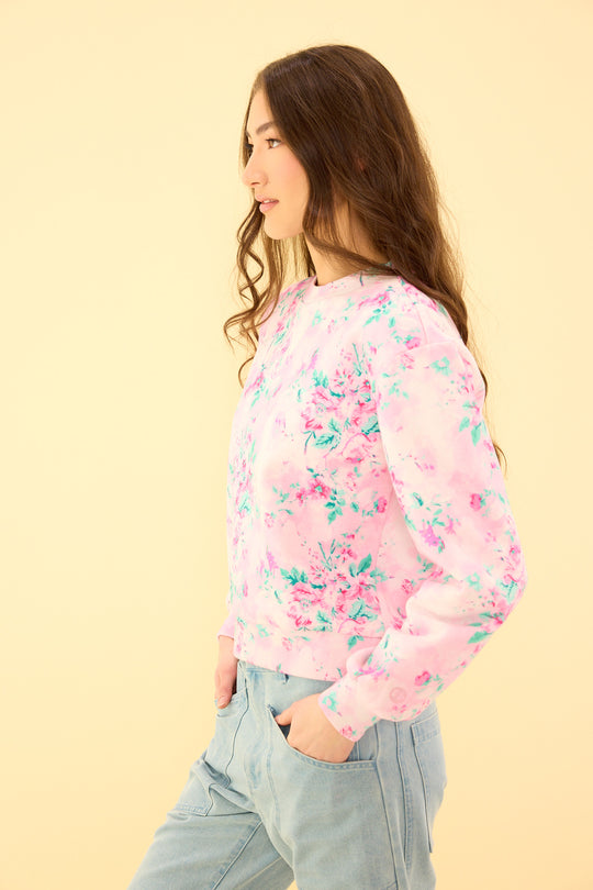 Woman wearing a pink floral sweatshirt against a beige background