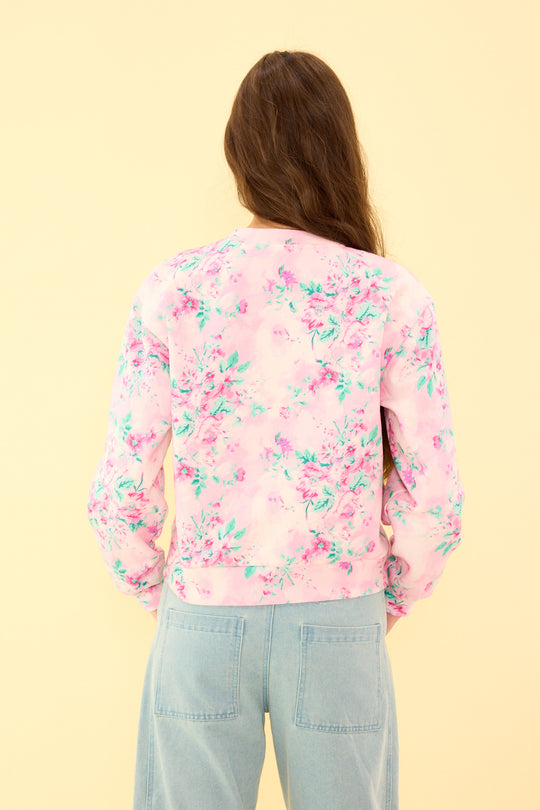 Person wearing a pink floral blouse against a yellow background