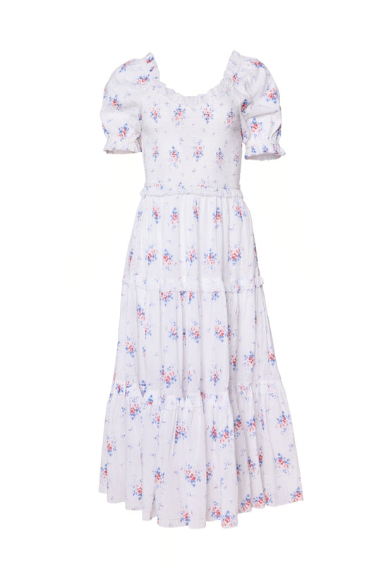 The Emily Dress in Heritage Soft Ditsy Floral by Ivy City Co is a light purple midi dress with puffed short sleeves, a smocked bodice, and a tiered skirt. The delicate pink and blue floral pattern throughout makes it ideal as both a maternity and nursing-friendly dress.