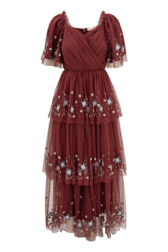 The Mabel Dress in Burgundy by Ivy City Co is a stunning maxi dress with layered tulle, short puff sleeves, a wrap-style bodice, blue and white floral embroidery, tiered silhouette, and delicate polka-dot details—perfect for a fall wedding.
