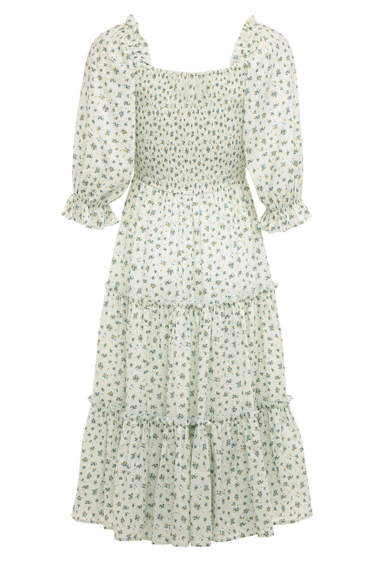The Madeline Dress in Blue by Ivy City Co is a light-blue floral midi dress with a smocked bodice, puffed half sleeves with ruffled cuffs, a tiered skirt, and a small floral print—maternity friendly for effortless elegance and comfort.
