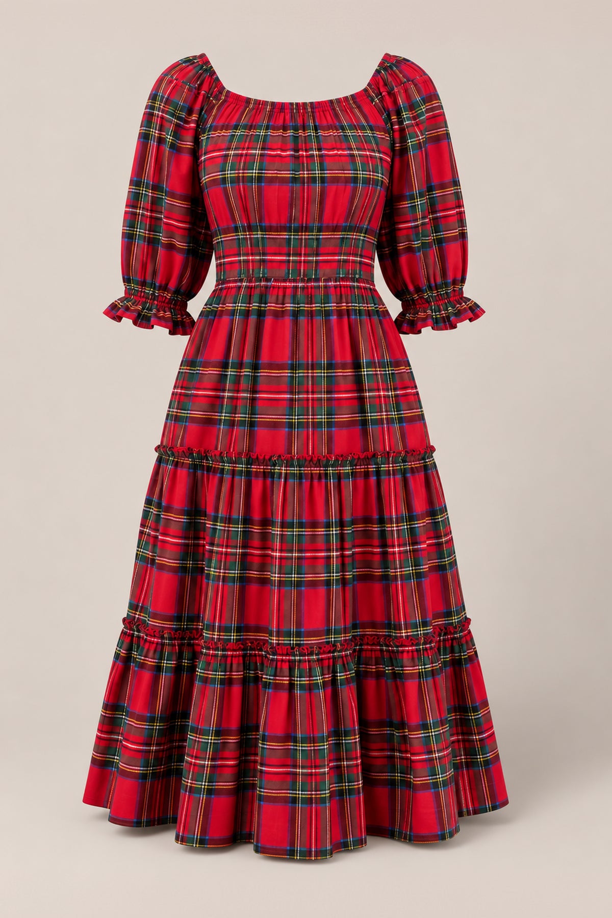 The Ivy City Co Madeline Dress in Holiday Plaid is a red, plaid, long-tiered dress featuring puffed mid-length sleeves, ruffle accents at the cuffs and seams, and a fitted waist. Both nursing friendly and maternity friendly, it is displayed against a plain beige background.