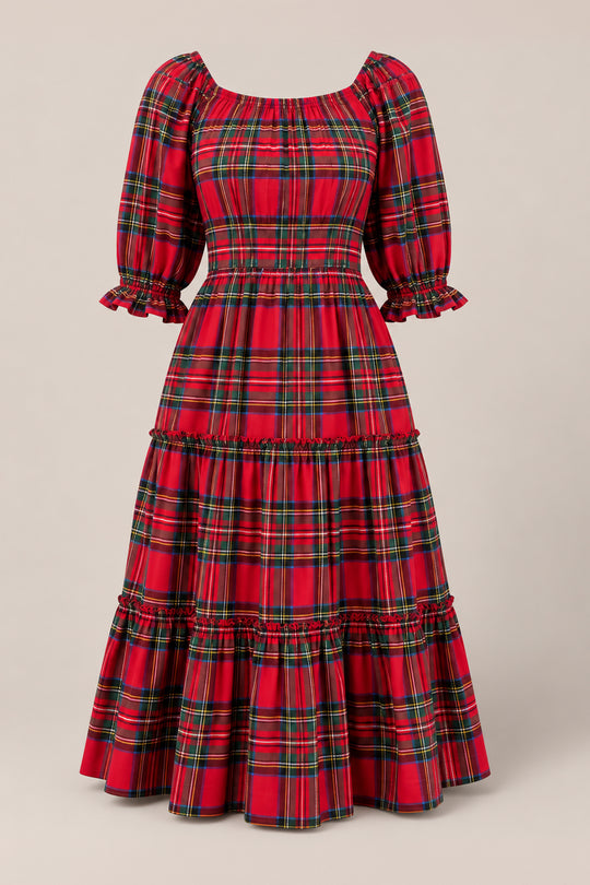 The Ivy City Co Madeline Dress in Holiday Plaid is a red, plaid, long-tiered dress featuring puffed mid-length sleeves, ruffle accents at the cuffs and seams, and a fitted waist. Both nursing friendly and maternity friendly, it is displayed against a plain beige background.