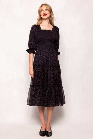 Woman wearing a black dress with a white pattern on a plain background