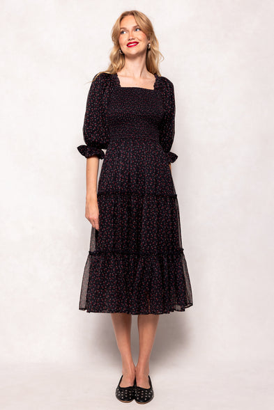 Woman wearing a black dress with a white pattern on a plain background