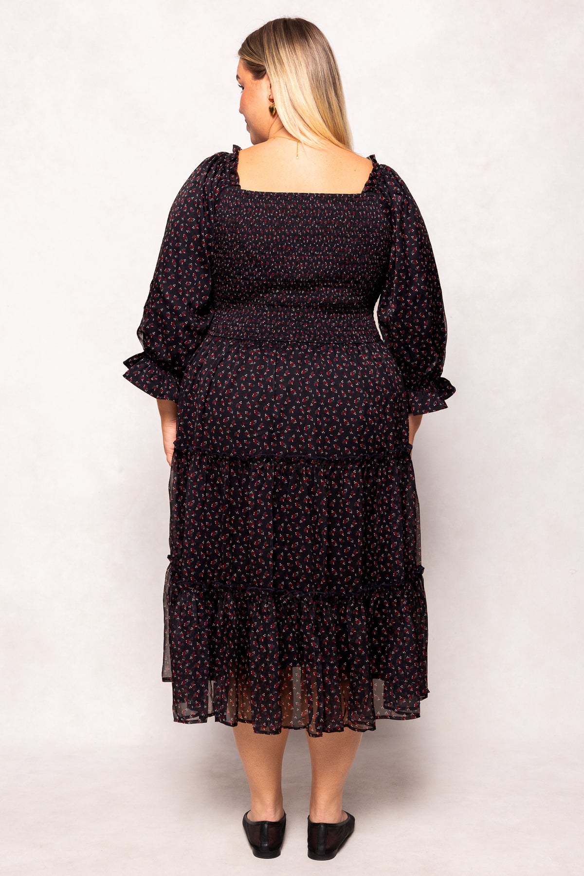 Woman wearing a black floral dress against a white background