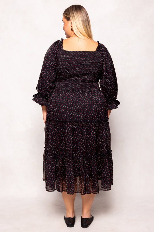 Woman wearing a black floral dress against a white background