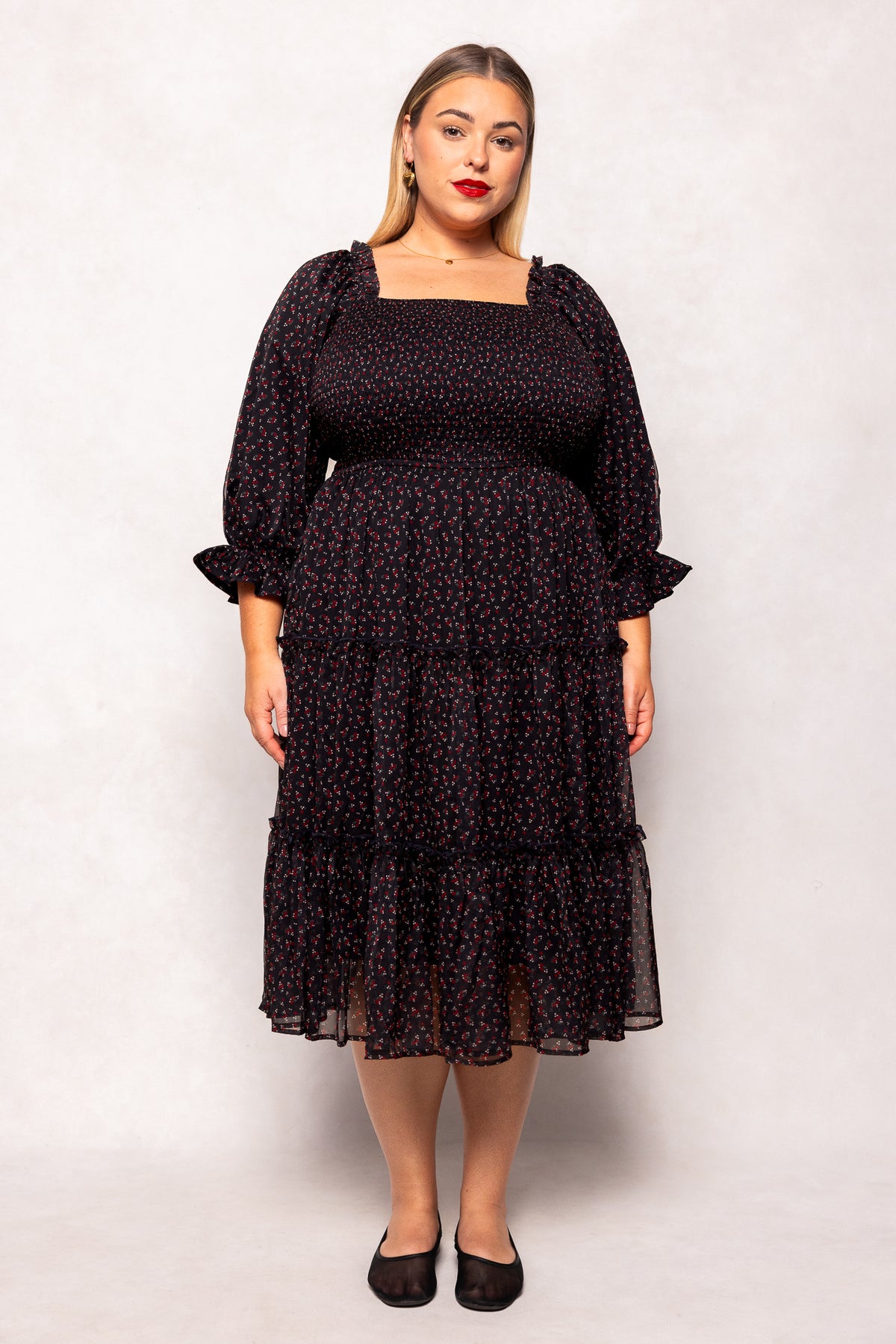 Woman wearing a black patterned dress against a white background