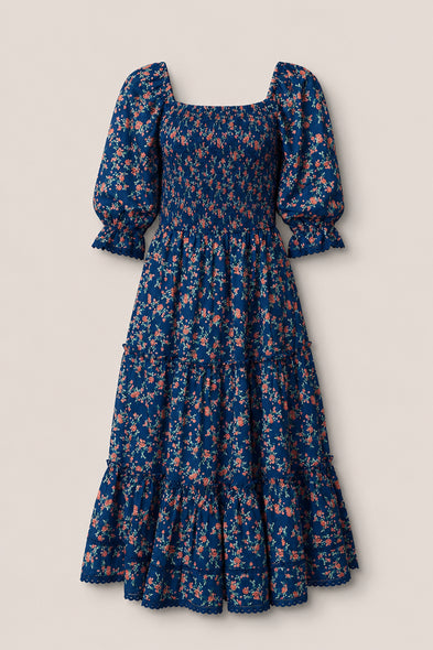 The Madeline Dress in Midnight Vibrant Chintz by Ivy City Co features a navy floral print, smocked bodice, puffed half sleeves, ruffled tiered skirt, and scalloped hem—an ankle-length maternity-friendly dress for any occasion.