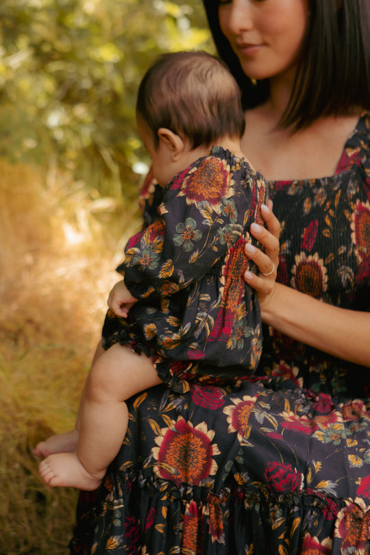 Woman and child wearing matching floral outfits in a natural setting