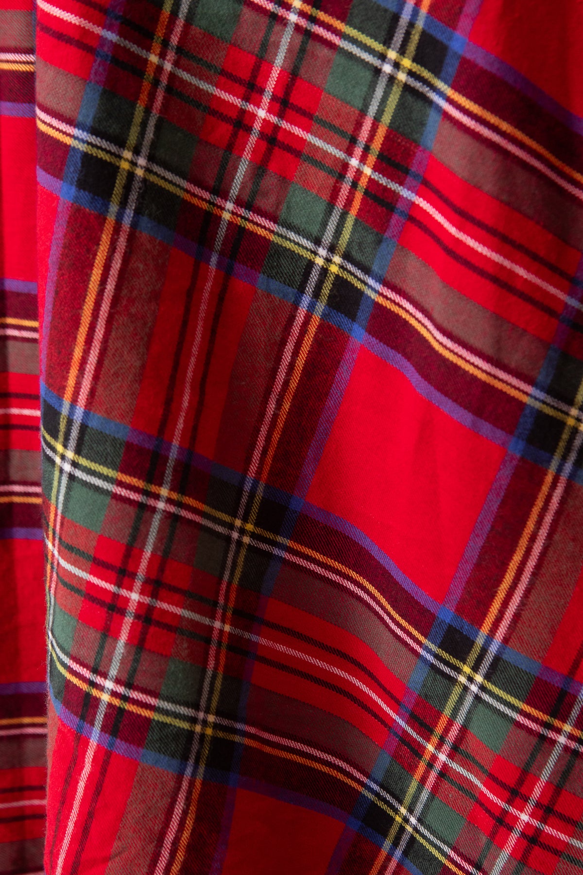 Close-up of red plaid fabric with a pattern of intersecting lines.