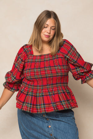 curve size woman wearing a red plaid top on a cream background