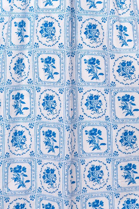 The Mae Dress in Blue Floral Stamp by Ivy City Co features blue and white fabric with a repeated square pattern, blue floral designs, and decorative borders—ideal for a charming blue floral look.