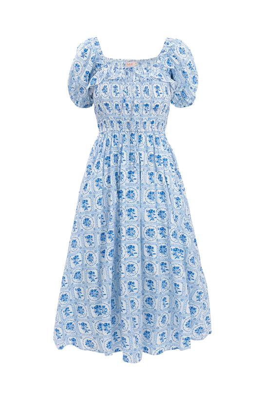 The Mae Dress in Blue Floral Stamp by Ivy City Co features light blue and white florals, puff sleeves, a smocked bodice, and a gathered skirt—perfect as a stylish maternity or nursing-friendly dress.